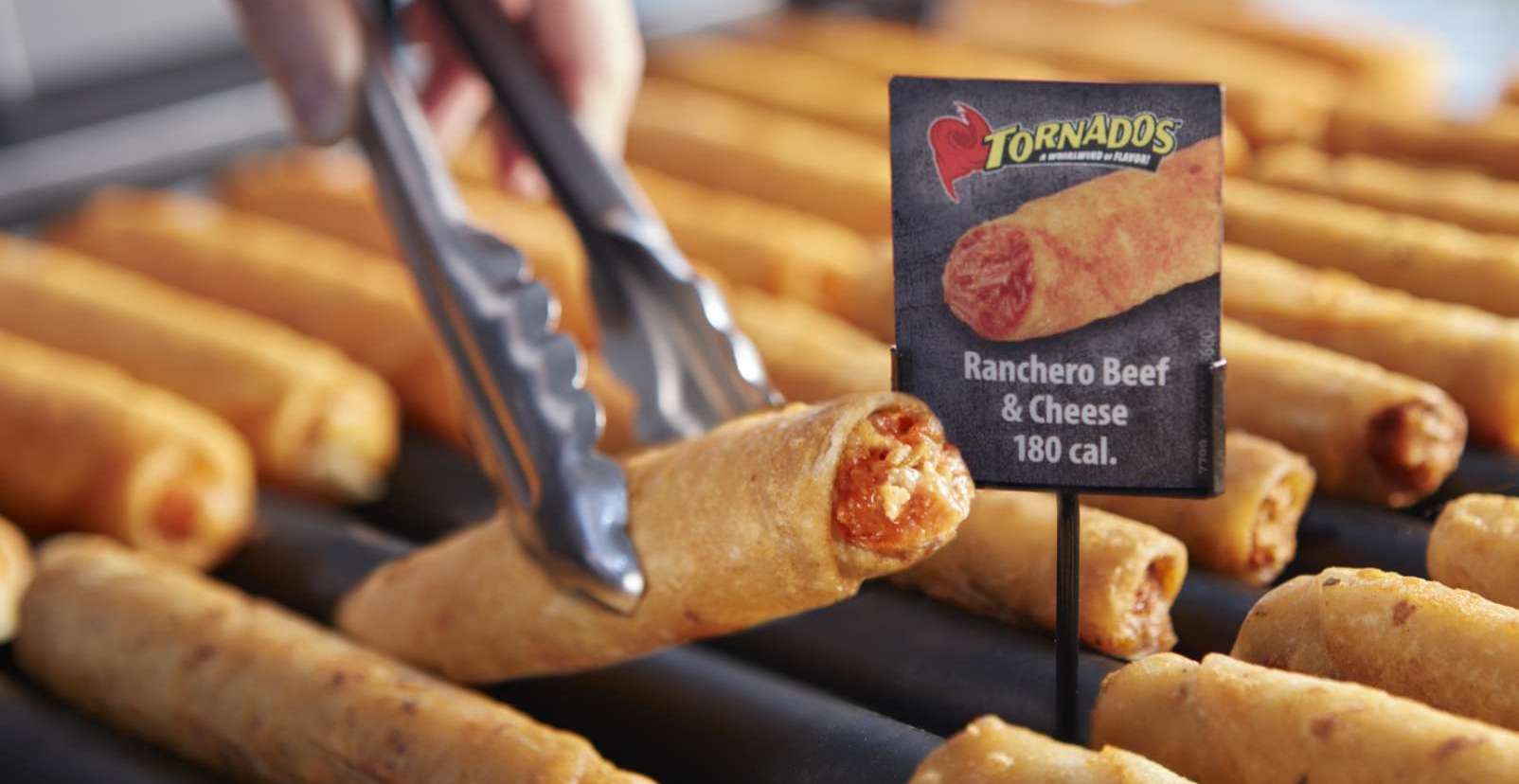 tongs picking up a tornados taquito from a roller grill