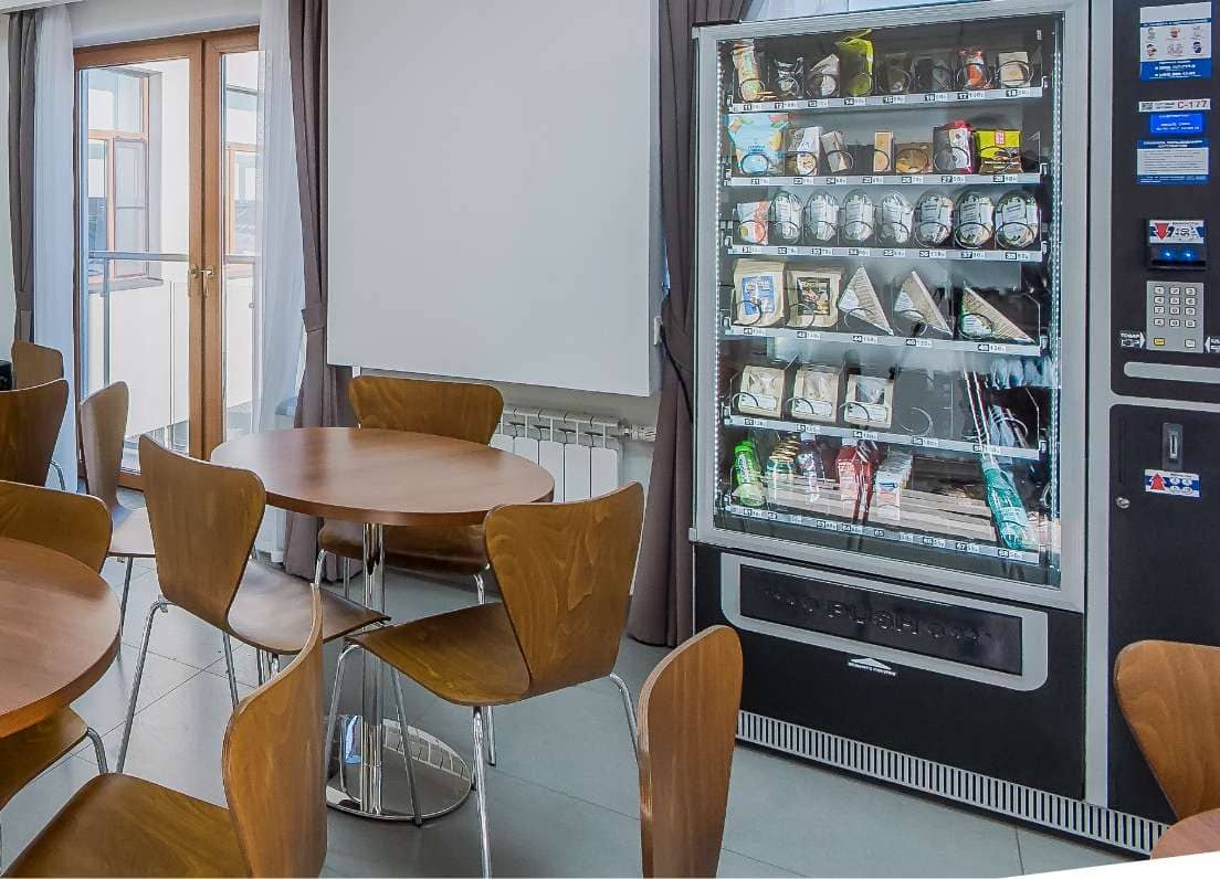 cafeteria with tables and chairs and a vending machine