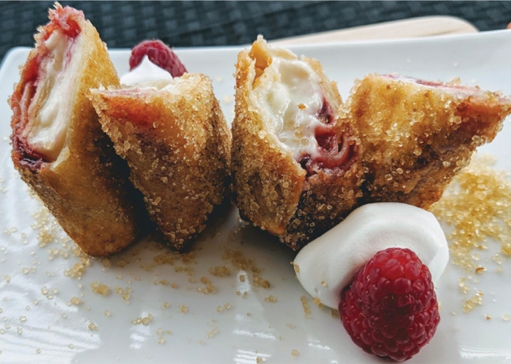 Raspberry Chimichangas Cut Open And Sprinkled With Sugar With Whipped Cream And Raspberry On The Side