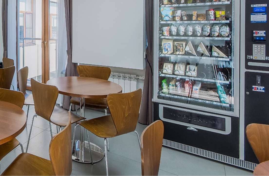 cafeteria with tables and chairs and a vending machine