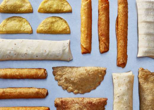 tornados taquitos, burrito and empanadas laid out on a blue surface