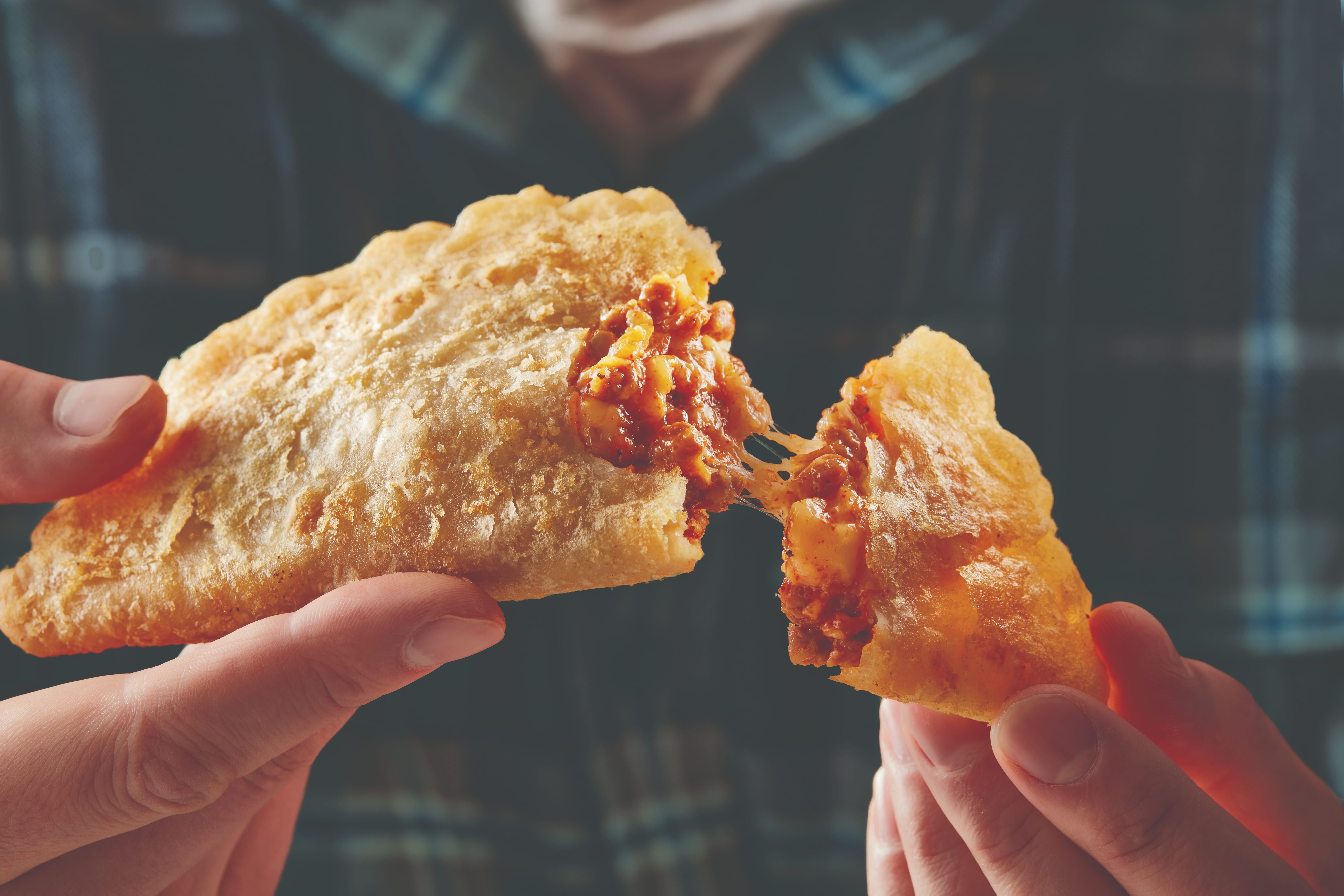 El Monterey Beef & Cheese Empanada being broken open and pulled apart to show filling