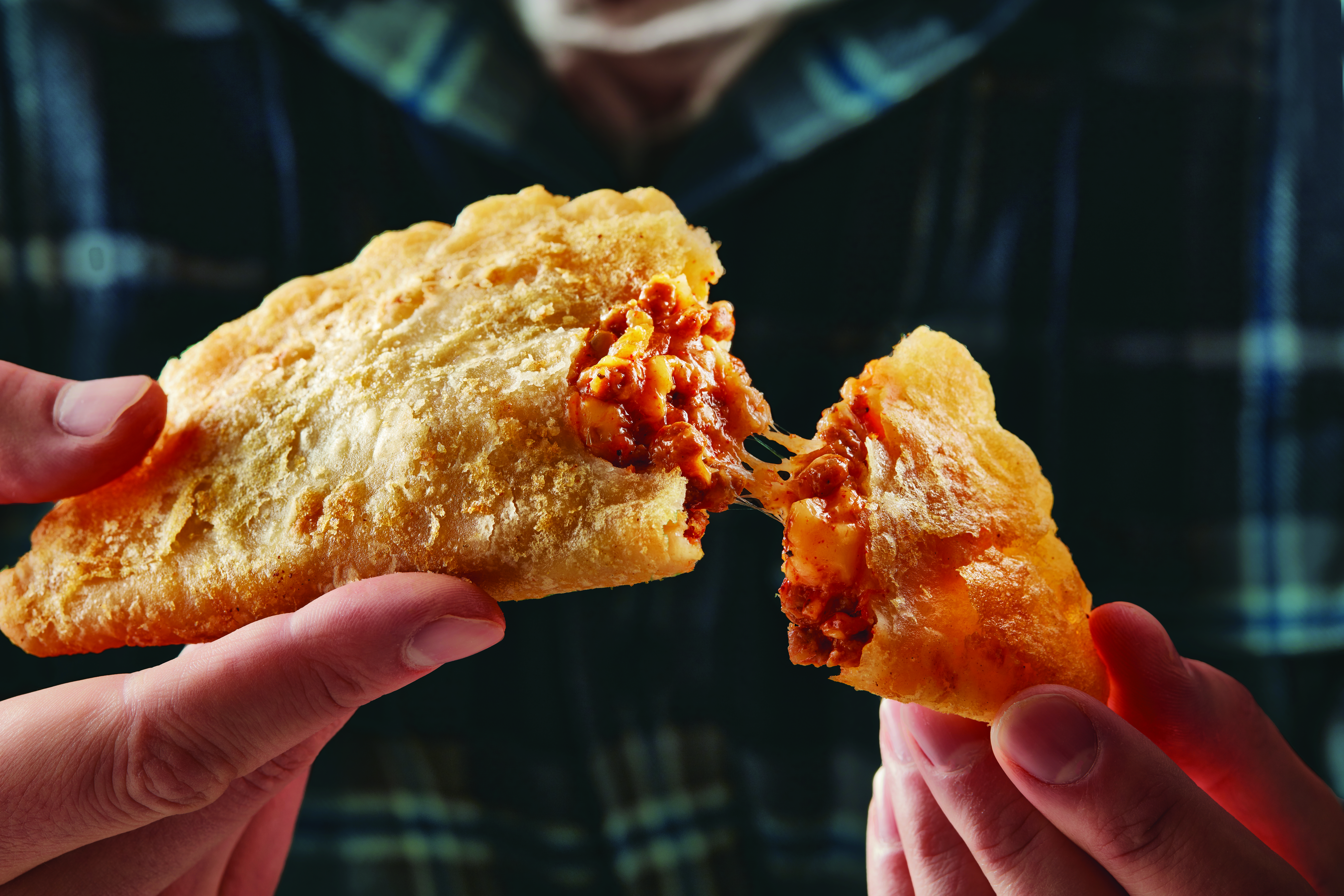 El Monterey Beef & Cheese Empanada being broken open and pulled apart to show filling