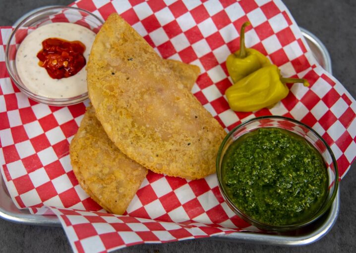 Cheesy Pepperoni Panadas Plated On A Metal Tray With Paper Lining Served With Pesto, A Dipping Sauce And Peppers