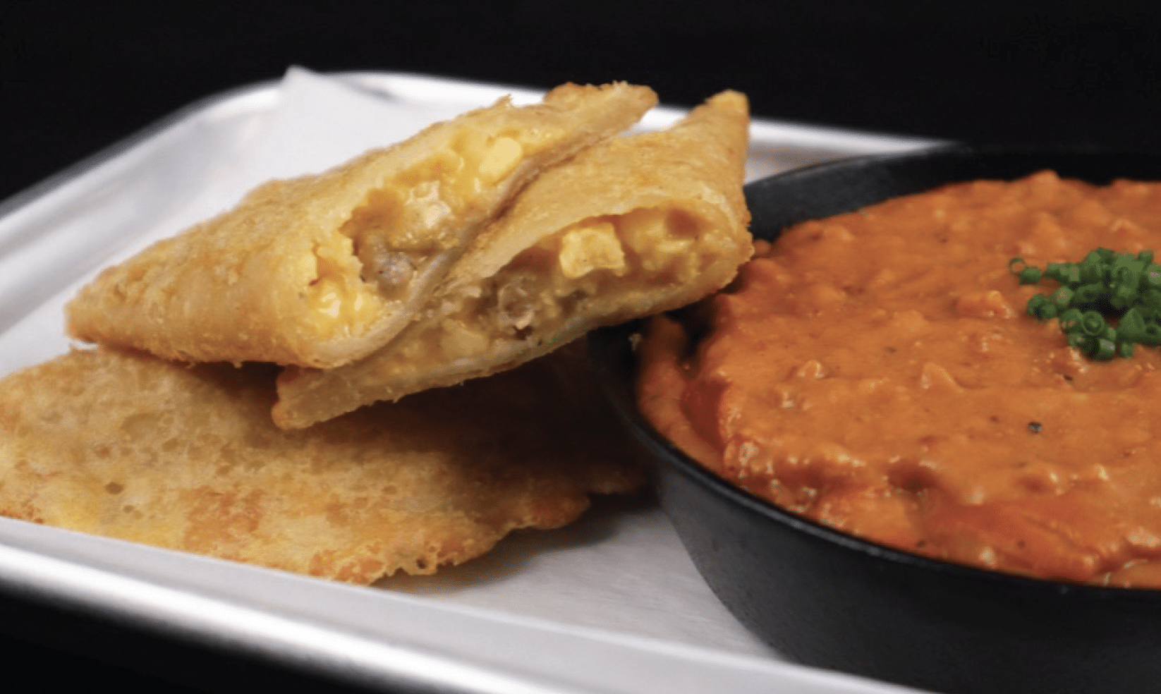 Two Sausage, Egg, Cheese & Potato Empanada plate and next to a dish of Mexican chorizo and gravy