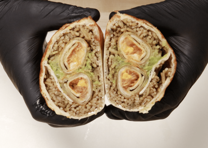 Burrito Stuffed With Tornados Cut Down The Middle And Held In Two Hands To Show The Filling