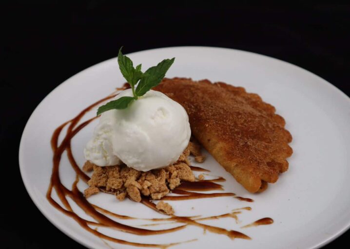 Apple Pie Empanada Plated And Next To Cinnamon Toast Crunch Topped With Vanilla Ice Cream, Cinnamon And Cinnamon Sauce