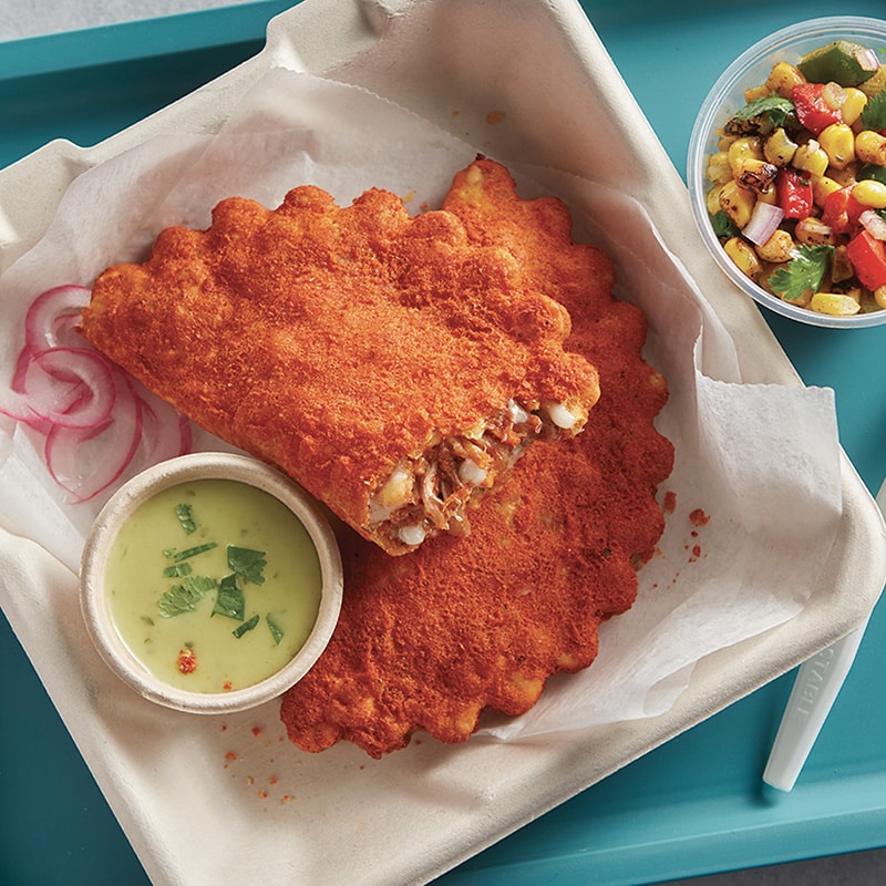 Two El Monterey Beef Birria Empanadas in a to-go container with a side of dip and salsa