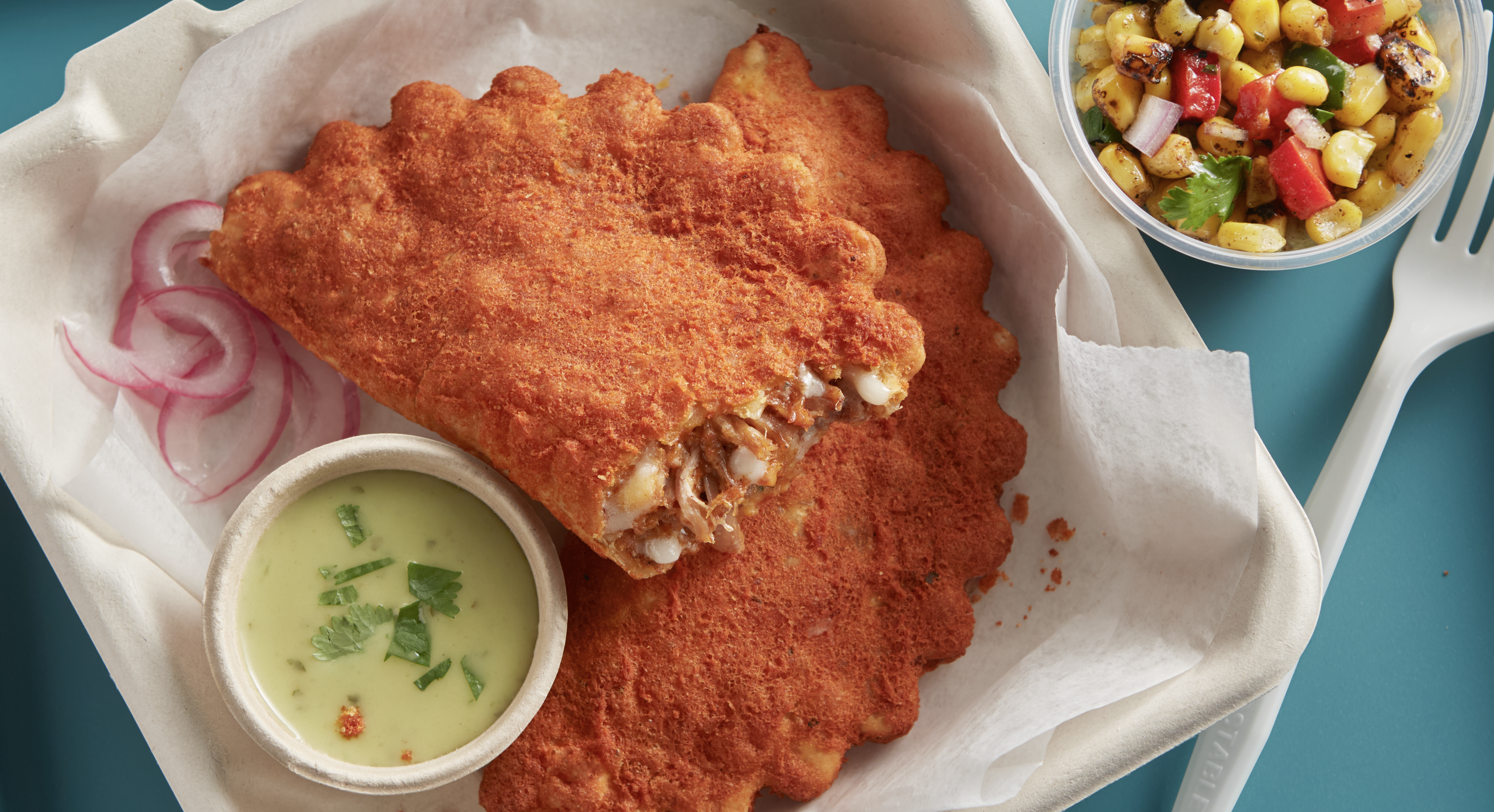 Two El Monterey Beef Birria Empanadas on a disposable to-go container with a side of pico and salsa